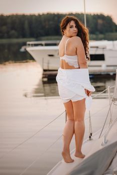 sexy woman in a white shirt enjoys the sunset on her private white yacht.