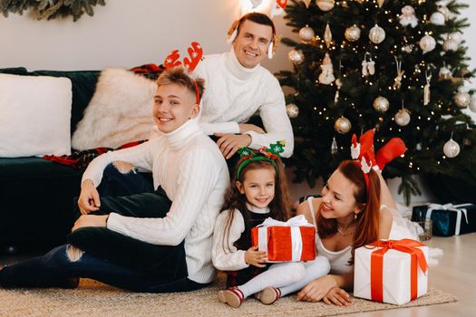 Happy family near the Christmas tree with gifts.