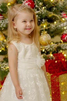 Beautiful little girl near the Christmas tree. The concept of family holidays, children's emotions.