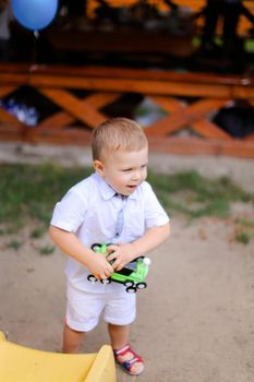 Little caucasian male child playing with toy car. Concept of childhood and toys.