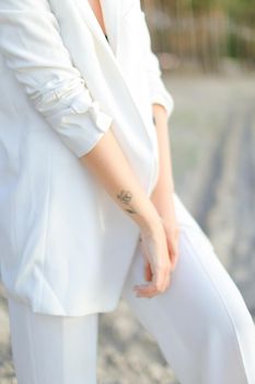 Close up female hands with little black tattoo in white clothes background.