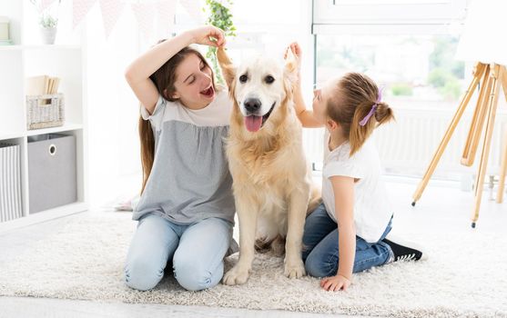 Cute sisters fooling with adorable dog's ears on floor at home