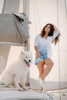 a happy woman with a big white dog on a white yacht in the sea.