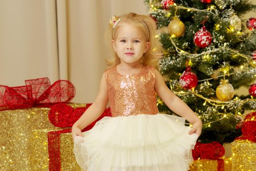 Beautiful little girl near the Christmas tree. The concept of family holidays, children's emotions.