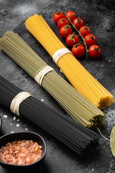 Multi colored spaghetti with ingredients set, on black dark stone table background