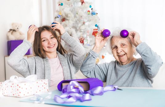 Smiling granddaughter ang grandma playing with decorative balls at Christmas