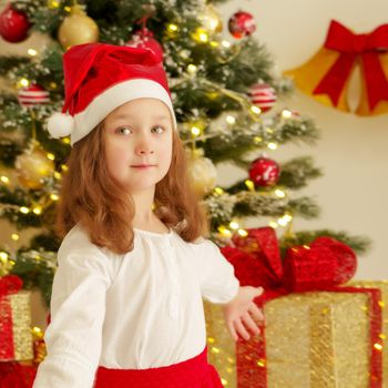 Beautiful little girl near the Christmas tree. The concept of family holidays, children's emotions.