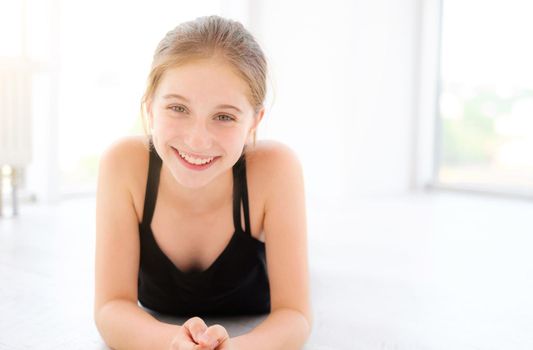 Beautiful teenager girl lying on a floor in light room