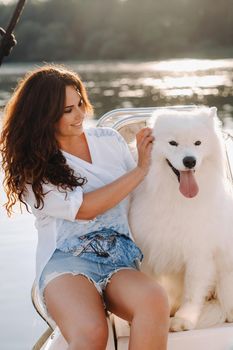 a happy woman with a big white dog on a white yacht in the sea.