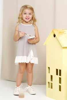 Joyful little girl draws with a brush and paints. The concept of children's creativity.