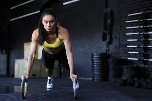 Sporty indian strong woman doing push-ups on rings