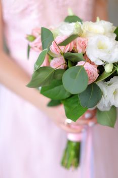 Close up bouquet of flowers in light pink dress background. Concept of wedding photo session and bride.