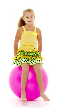 A little girl is jumping on a big ball for fitness. The concept of sport and a healthy lifestyle. Isolated on white background.