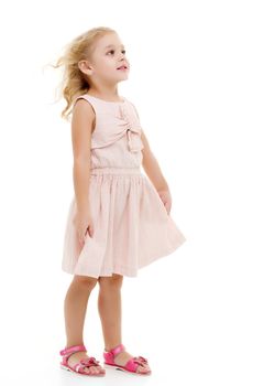 Portrait of a positive and stylish little girl in a summer dress, rejoices in the wind that blows and moves her dress and hair. The concept of beauty and fashion. Isolated on white background.