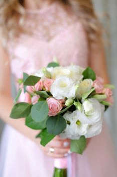 Close up cute bouquet of flowers in light pink dress background. Concept of wedding photo session and bride.