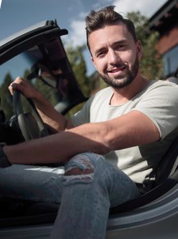 close up.handsome young man sitting in convertible car.the concept of a successful lifestyle