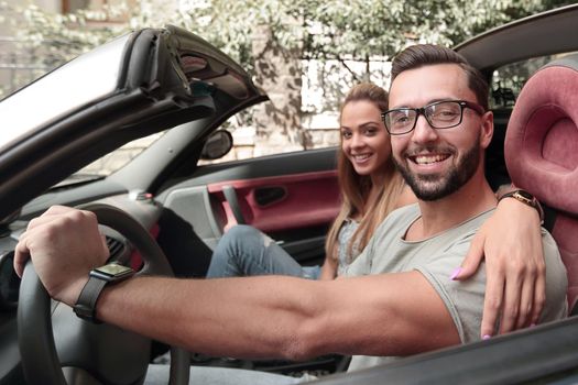 young couple inside a convertible car for a day trip.the concept of the relationship