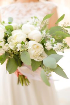 Close up amazing bouquet of white flowers in dress background. Concept of wedding photo session and floristic art.