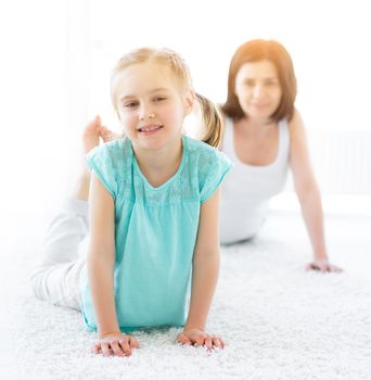 Pretty little girl doing physical exercises with mother at home