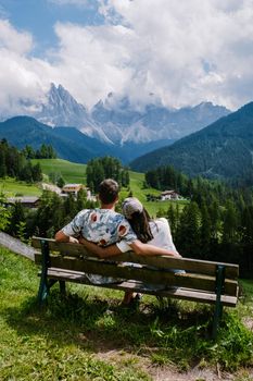 Santa Magdalena village in Val di Funes on the italian Dolomites. Autumnal view of the valley with colorful trees and Odle mountain group. Italy, man and woman on vacation, hiking in the mountains