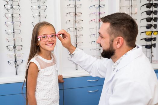 Little girl and doctor ophthalmologist choose glasses
