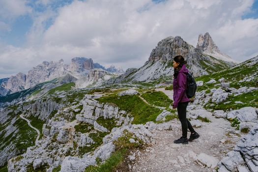 Tre Cime di Lavaredo peaks or Drei Zinnen at sunset, Dobbiaco Toblach, Trentino -Alto Adige or South Tyrol, Italy. Europe Alps. Asian woman hiking in the mountains