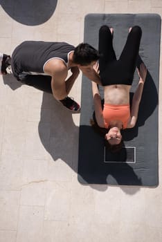 young handsome woman with personal trainer doing morning yoga exercises in front of her luxury home villa top view