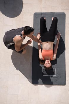 young handsome woman with personal trainer doing morning yoga exercises in front of her luxury home villa top view