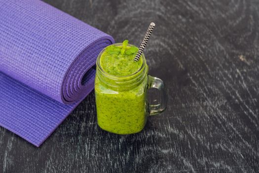 Green smoothies made of spinach and pineapple and a yoga mat. Healthy eating and sports concept.