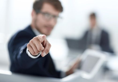 a young business man points a finger at the camera, in his hand holds a tablet