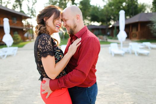 Bald husband wearing red shirt and dancing with wife on backyard. Concept of weekends and resting, relationships and happy couple.