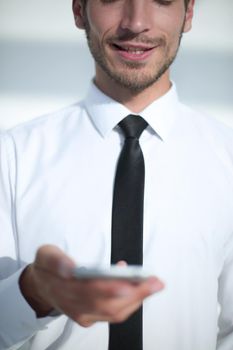 a young businessman is standing with a phone in his hands in the office. a large plan.