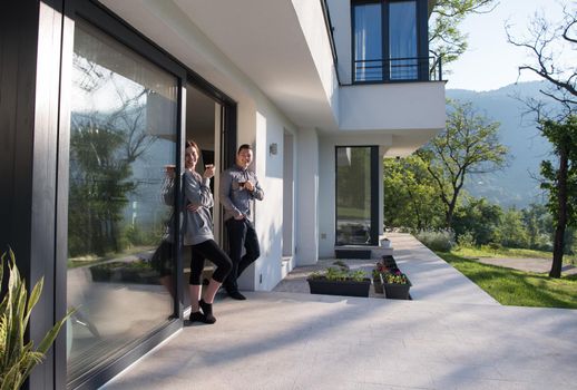 young beautiful handsome couple enjoying morning coffee on the door of their luxury home villa