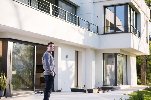 portrait of a young handsome successful man in front of his luxury home villa