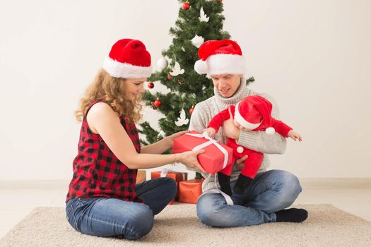 Happy couple with baby celebrating Christmas together at home