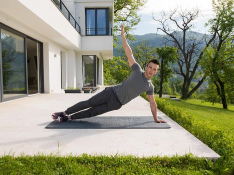 young handsome man doing morning yoga exercises in front of his luxury home villa