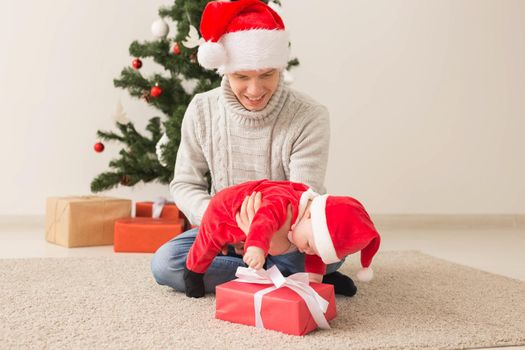 Father with his baby boy wearing Santa hats celebrating Christmas