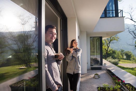 young beautiful handsome couple enjoying morning coffee on the door of their luxury home villa