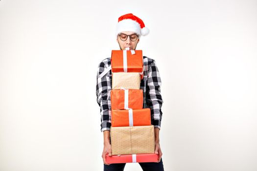 Holidays and presents concept - Funny man in Christmas hat holding many gift boxes on white background.