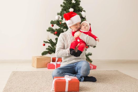 Father with his baby boy wearing Santa hats celebrating Christmas