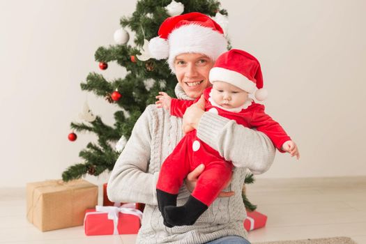 Father with his baby boy wearing Santa hats celebrating Christmas