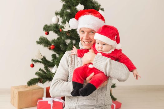 Father with his baby boy wearing Santa hats celebrating Christmas