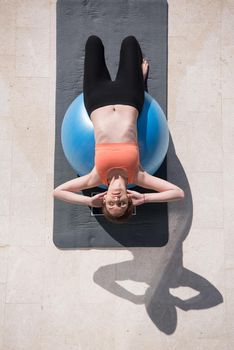young beautiful woman doing exercise with pilates ball in front of her luxury home villa top view
