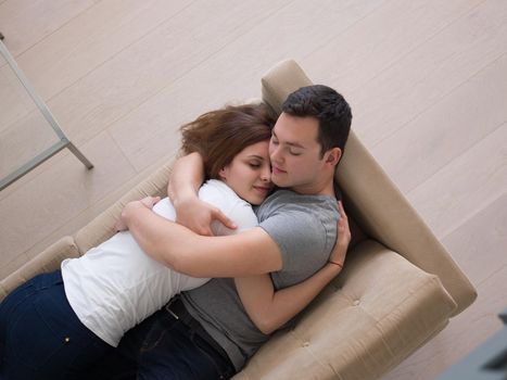 young handsome couple enjoys hugging on the sofa in their luxury home villa