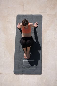 young handsome woman doing morning yoga exercises in front of her luxury home villa top view