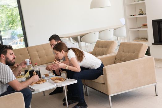 a group of young people cheerfully spending time while eating pizza in their luxury home villa