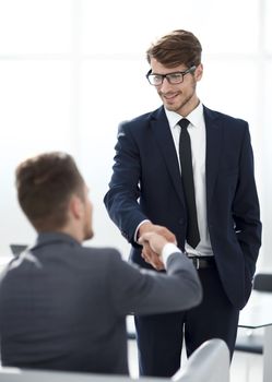 young businessman with glasses greets his colleague with a handshake