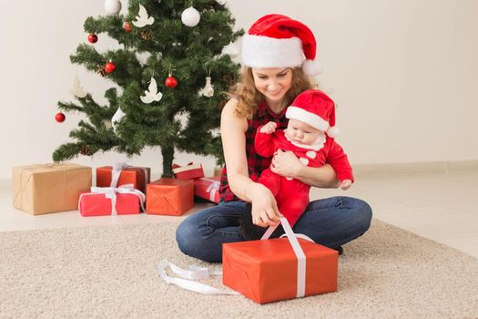 Family, childhood and Christmas concept - Portrait of happy mother and adorable baby in suit of Santa.