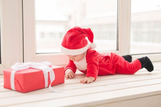 Beautiful little baby celebrates Christmas. New Year's holidays. Baby in a Christmas costume and in santa hat.