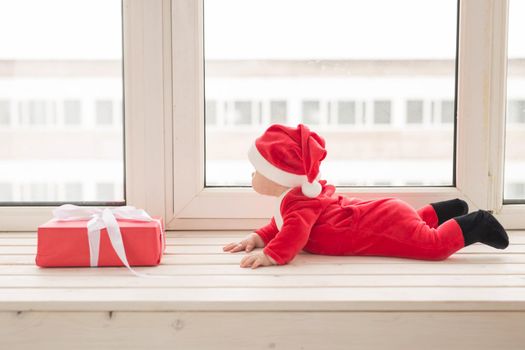 Beautiful little baby celebrates Christmas. New Year's holidays. Baby in a Christmas costume and in santa hat.